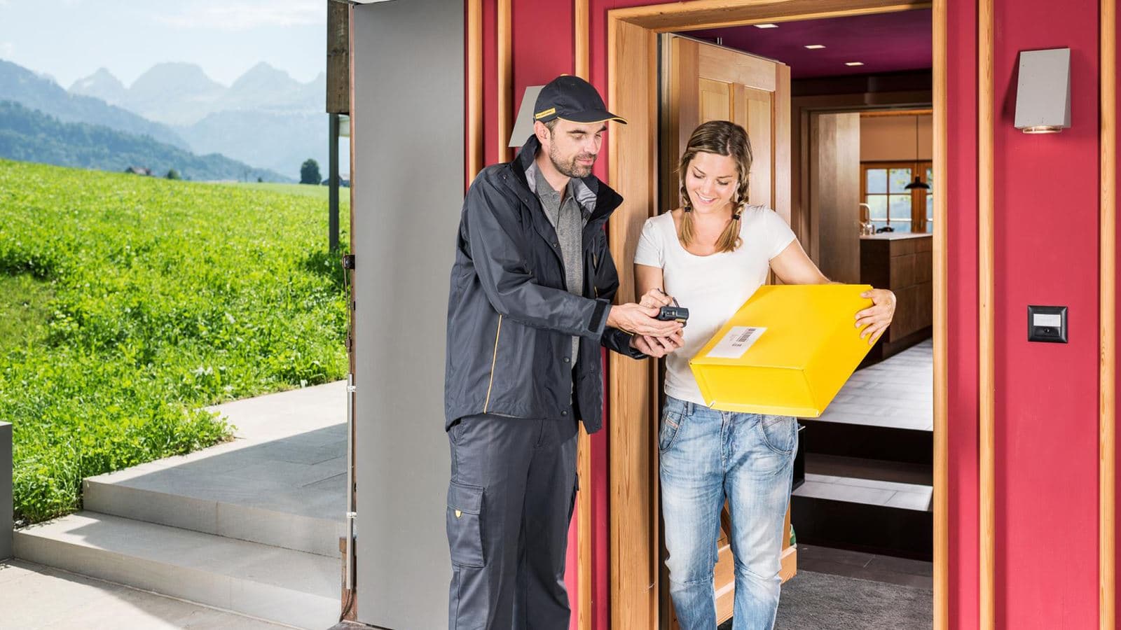 Zusteller der Schweizerischen Post übergibt ein Paket gegen Unterschrift